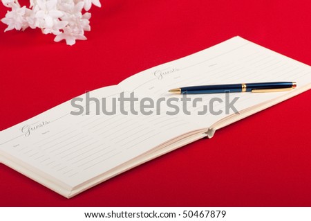 Opened wedding guest book with a pen on a red background