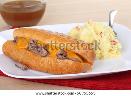 French dip roast beef with melted cheese sandwich with potato salad and juice dip