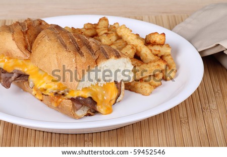 Roast beef sandwich covered with melted cheese on grilled French bread and french fries