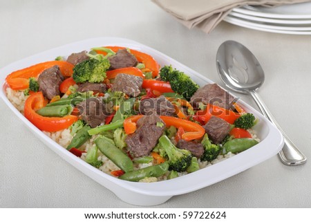 Beef stir fry with broccoli, red peppers and pea pods over rice
