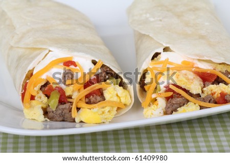 Breakfast burritos made with sausage, scrambled eggs, cheese, tomatoes wrapped in tortillas