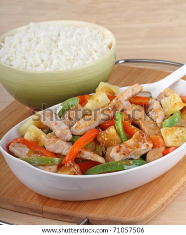 Sweet and sour pork with green and red peppers and a bowl of rice