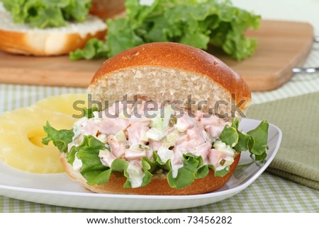 Ham salad with lettuce on a bun and pineapple slices