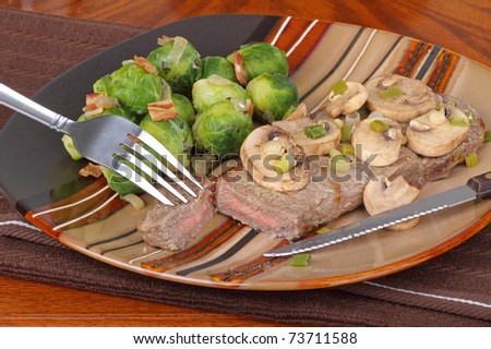 New York strip steak topped with mushrooms and brussels sprouts