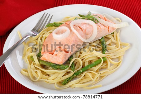 Poached salmon fish fillet with asparagus and noodles on a dinner plate