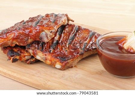 Grilled barbecue spareribs and barbecue sauce on a cutting board