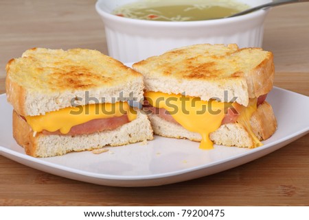 Grilled ham and cheese sandwich with soup in the background