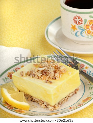 Lemon square dessert with lemon slices on a plate and cup of coffee