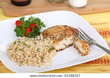 Breaded fried chicken with brown rice on a dinner plate