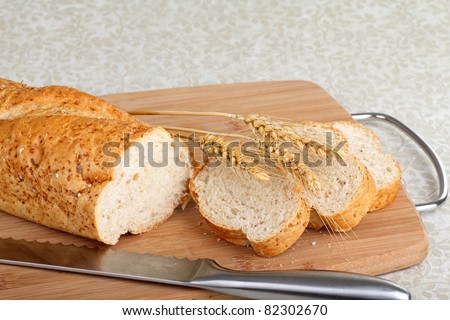 Sliced wheat bread with wheat heads on a cutting board
