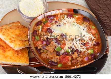 Bowl of chili with melted cheese and cheese bread