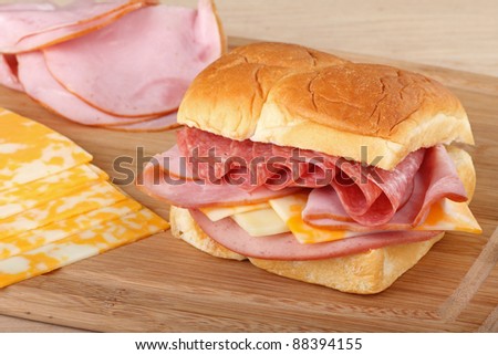 Sandwich with ham, pepperoni, cheese and bologna with ham and cheese slices on the side