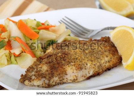 Closeup of a breaded catfish fillet with a lemon slice