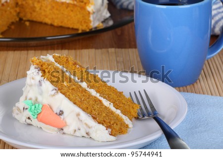Slice of carrot cake on a plate with a cup of coffee