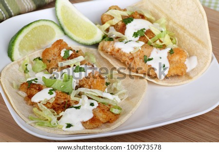 Two fish tacos with sliced lime on a plate