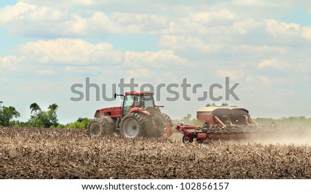 Red tractor pulling a sprayer applying chemicals to farm field