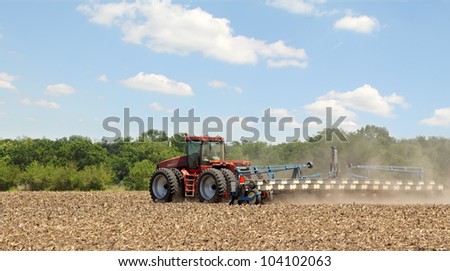 Red tractor planting crop in farm field