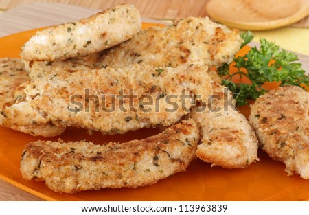 Chicken breast tenderloins on an orange platter