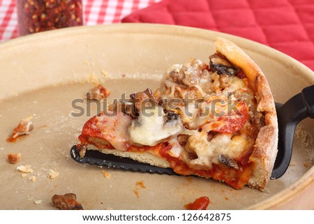 Slice of deep dish pizza in a pizza pan