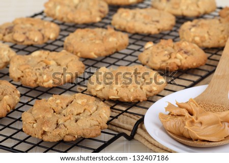 Peanut butter cookies on a cooling rack with a spoon of peanut butter on side