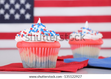 Red, white and blue cupcakes with american flag in background