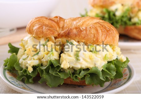 Closeup of an egg salad sandwich on a croissant bun