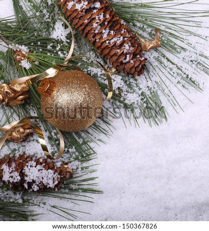 Gold Christmas ball, pine cone and branches in the snow
