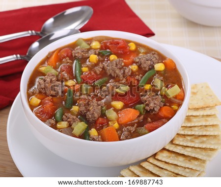 Bowl of vegetable and beef soup with crackers