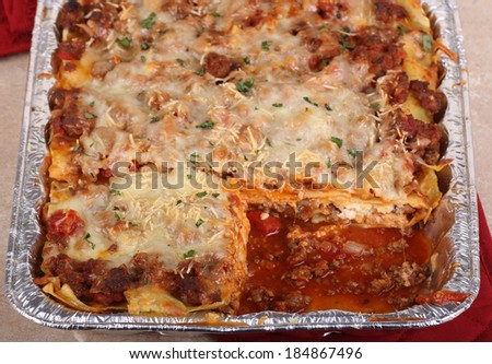 Lasagna meal in a baking pan with a piece cut out