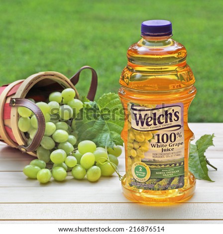 PETERSBURG, ILLINOIS-AUGUST 1, 2014:  Bottle of Welch\'s white grape juice with grapes in background on a table outside.  Welch Food Inc. is owned by the National Grape Cooperative Association.