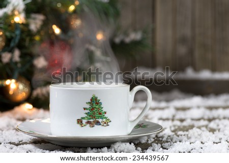 Christmas coffee cup on snowy deck with decorations in background