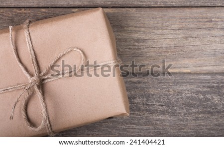 Closeup of a brown package tied with string on a wood background