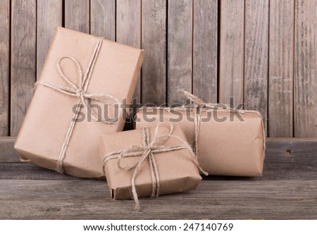 Three packages wrapped in brown paper and string on old wood deck