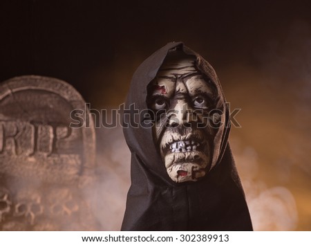 Scary zombie halloween prop with a tombstone and smoky background