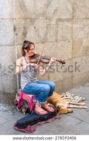 MADRID - August 31: The unknown woman plays a violin for money on the street, August 31, 2014 in Madrid, Spain. A report shows 22% of households in Spain live below the poverty line.