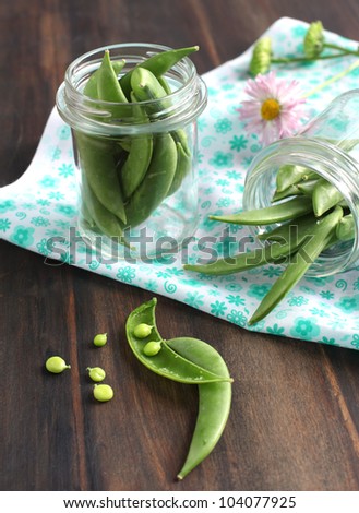 Snow peas pods in jar on a wooden table