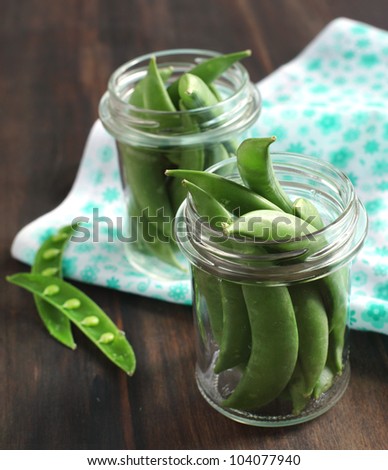 Snow peas pods in jar on a wooden table