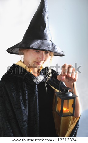 Portrait of girl in black hat and black clothing with candle