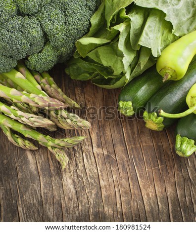 Fresh green vegetables on a wooden background.