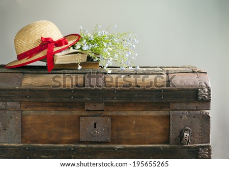Summer blue flowers, old books and straw hat on old vintage ches
