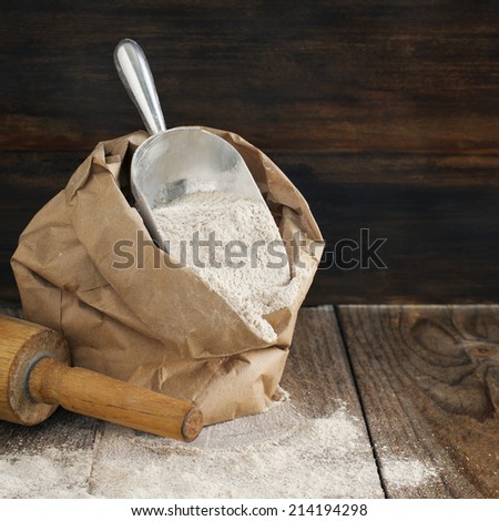 Rye flour in brown paper bag on wooden background.