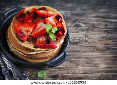 Stack of pancakes with fresh strawberry and balsamic glase in frying pan