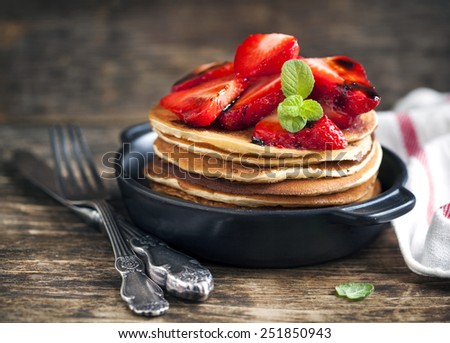 Stack of pancakes with fresh strawberry and balsamic glase in frying pan