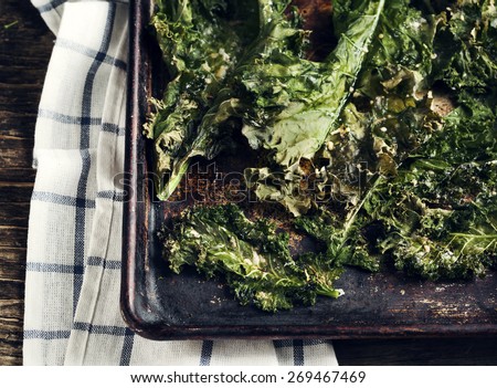 Crispy cheese and chili kale chips on baking tray. Toned image
