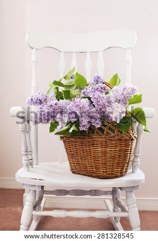 Vintage chair with bouquet of lilac in basket