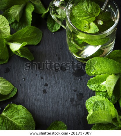 Mint tea and mint leaves over black background with copy space.