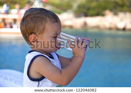 lovely handsome boy is drinking water on a boat