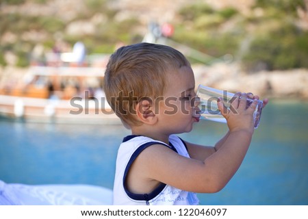 lovely handsome boy is drinking water on a boat