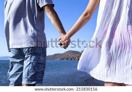 Young couple hand to hand at the beach