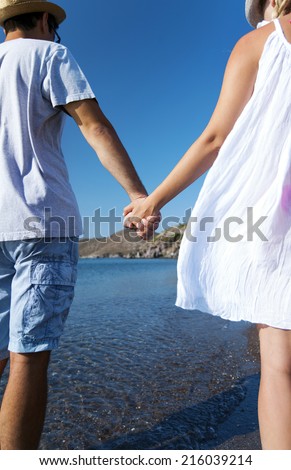 Young couple is walking on the beach hand to hand